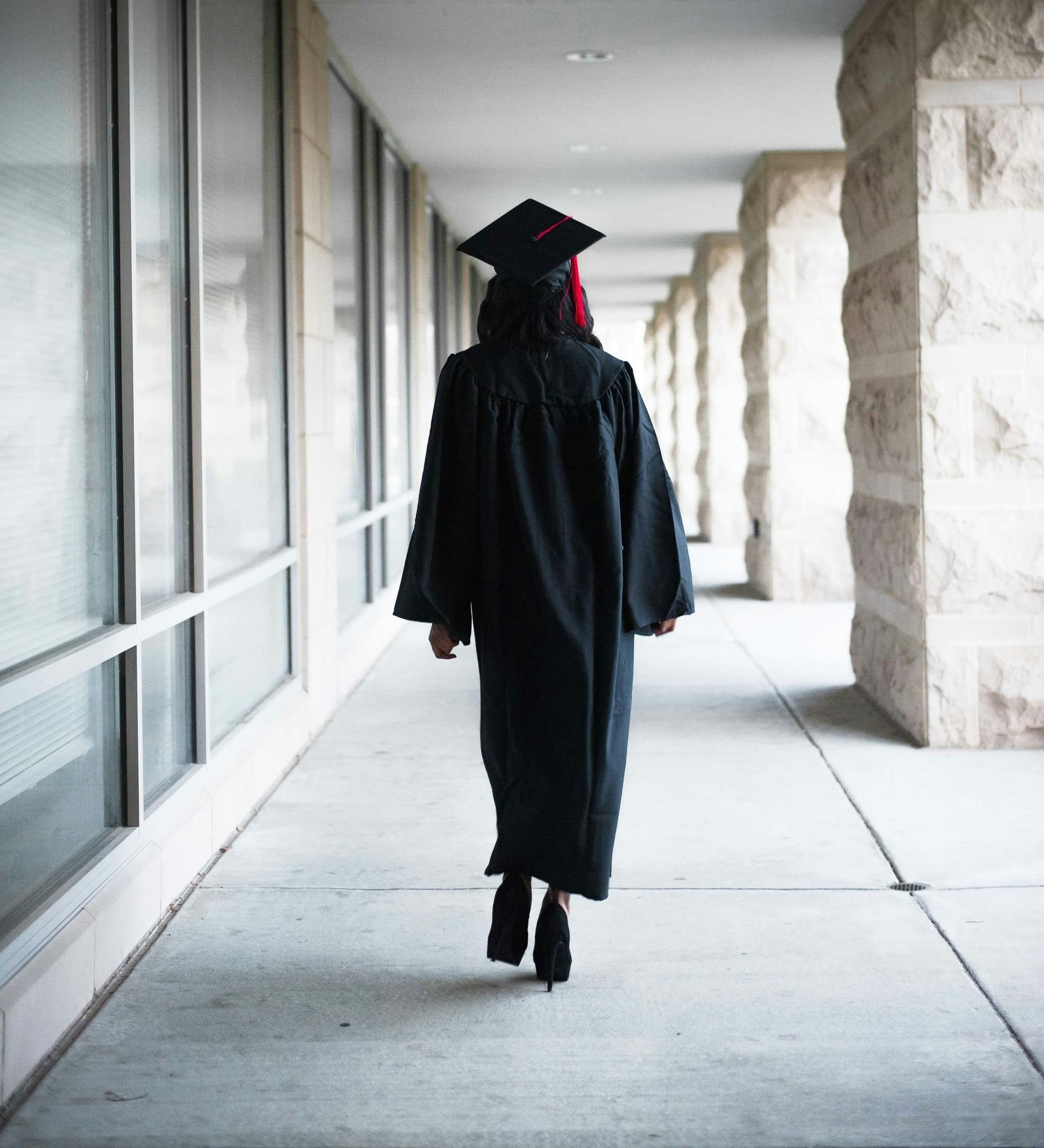 a person in a graduation gown walking down a hallway