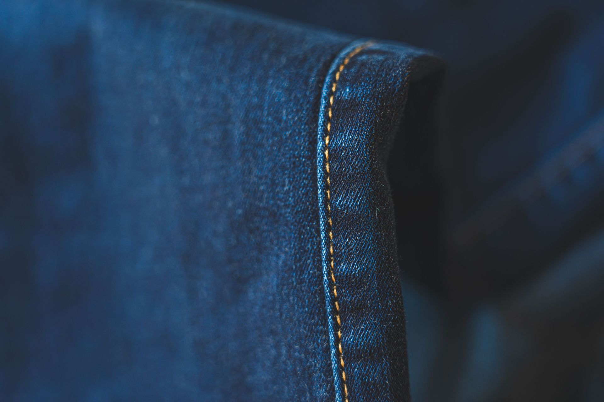 Detailed close-up of blue denim fabric showcasing intricate stitching. Ideal for fashion and textiles.