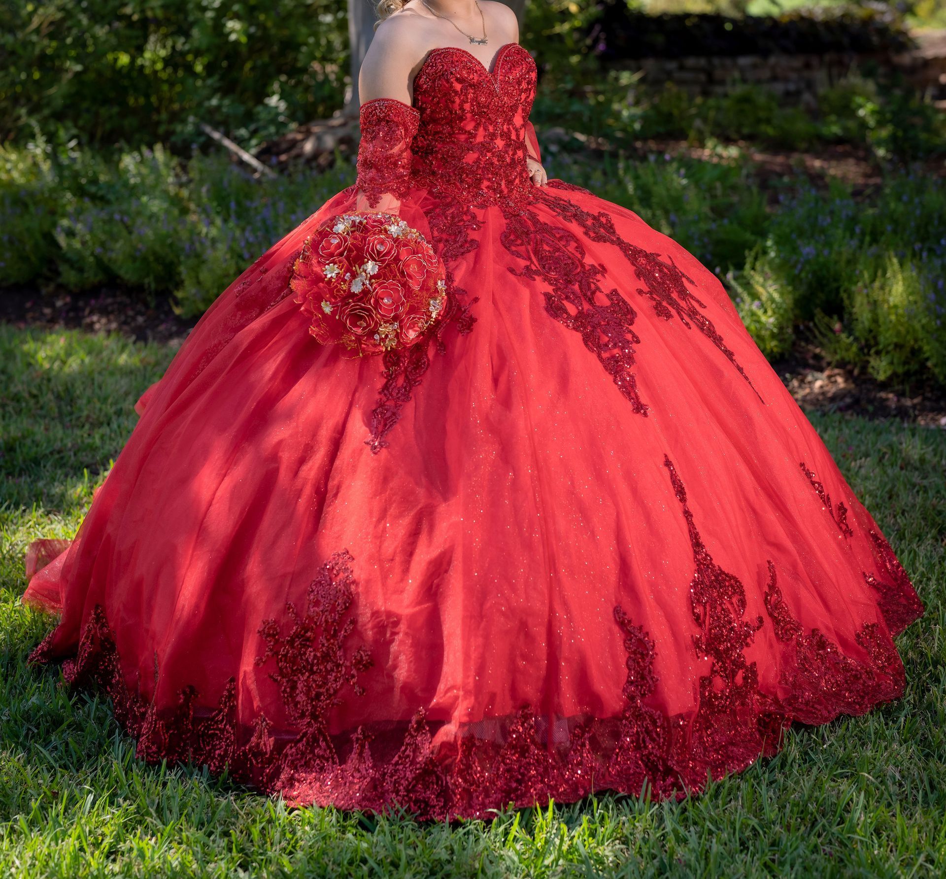 Portrait of a young woman in a red quinceañera dress outdoors, showcasing elegance and youth.